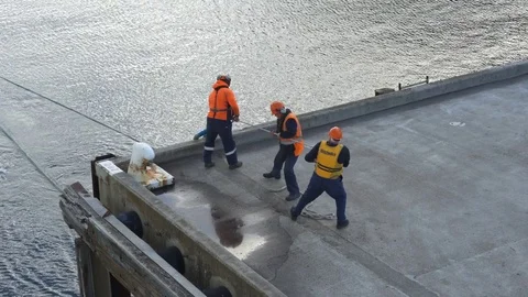 Dock workers pulls on heavy rope in the industrial port Stock Footage 76424128