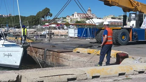 Dock workers secure sailing yacht for crane lift in Cagliari, Sardinia Stock Footage 310252263