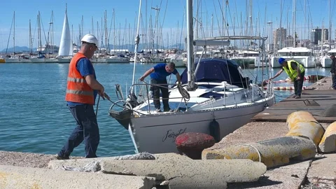 Dock workers secure sailing yacht for crane lift in Cagliari, Sardinia Stock Footage 310252469