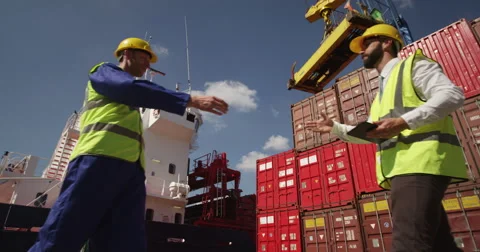 Dock workers shake hands and discuss shipping logistics in a shipyard. Stock Footage 54928825