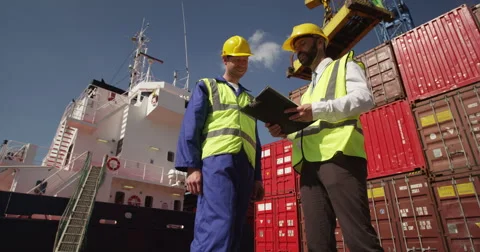 Dock workers shake hands and discuss shipping logistics in a shipyard. Stock-Footage 55024644