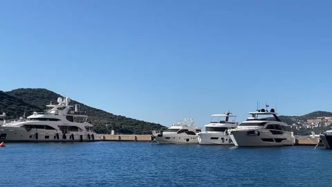 Docked yachts against clear blue sky in marina with hills and distant build.. Video stock 329621777
