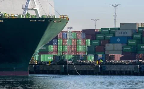 Dockworkers tying up container ship to dock with stacked containers background Stock Photos