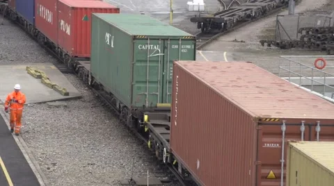 Dockyard shipping containers pulled on train with workmen walking beside Video stock 55044173