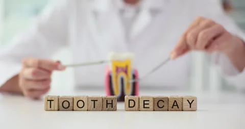 Doctor and artificial tooth model using dental instruments word tooth decay Stock Footage 252932319