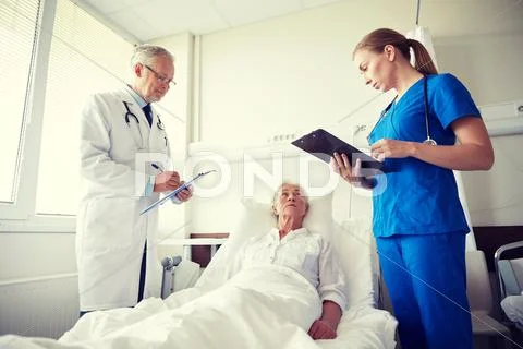 Doctor and nurse visiting senior woman at hospital Stock Photos