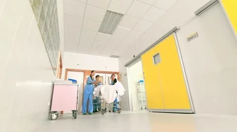 Doctor and nurses driving a patient on his bed Stock Footage