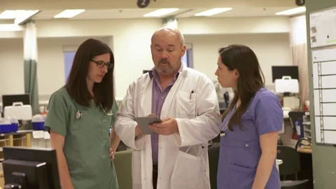 Doctor and Nurses review data on a tablet computer. Video stock 81170326