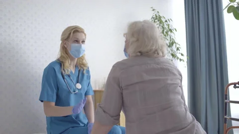 Doctor and senior patient talking in face masks, infectious disease prevention Stock Footage