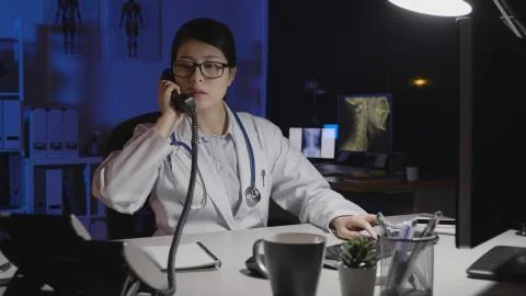 Doctor answer phone call while using computer Stock Photos