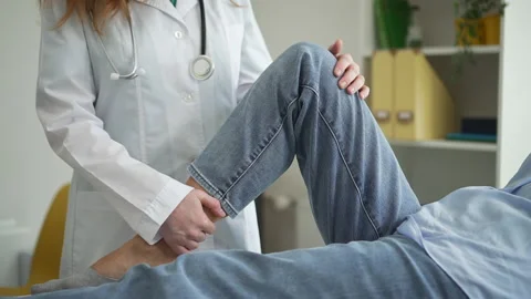 Doctor at appointment with client lady bends leg checks knee Spbd Video stock 159500589
