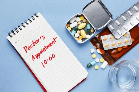 Doctor appointment note with pills on table Stock Photos