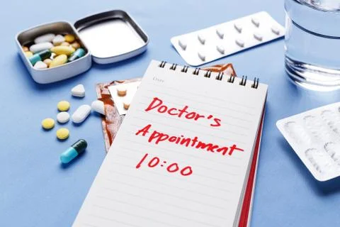 Doctor appointment note with pills on table Stock Photos