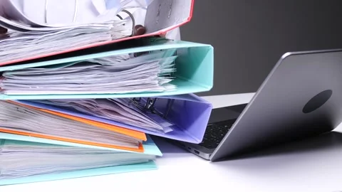 Doctor attending to a large stack of patient files and documents, indicating an Stock Footage 324767542