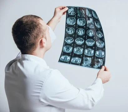 Doctor attentively examines the MRI scan of the patient. Stock Photos