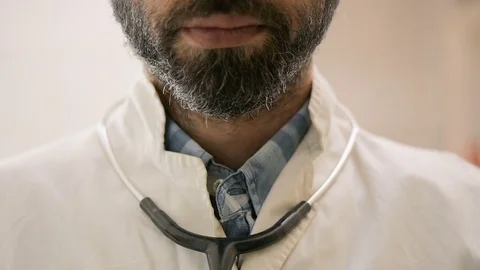 Doctor with beard is putting his stethoscope on his head Stock Footage 78347853