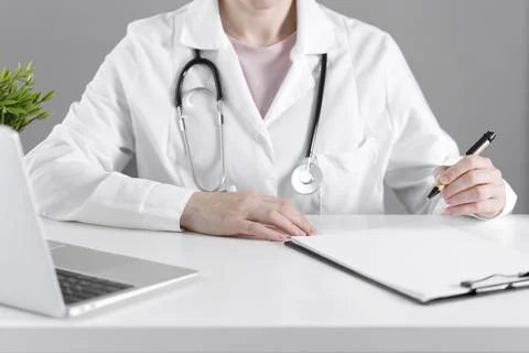 The doctor behind the white writes data on paper. Фото