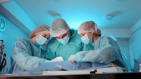 The doctor is being assisted by two nurses during the operation procedure Stock Footage 233680915