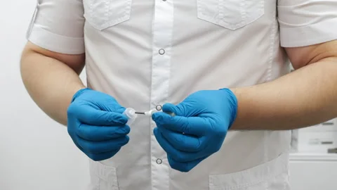 Doctor in blue gloves preparing needle for blood test in medical laboratory. 動画素材 321576625