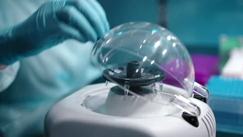 A doctor in blue surgical gloves puting a sample in a small tube in a centrifuge Video stock 237199161