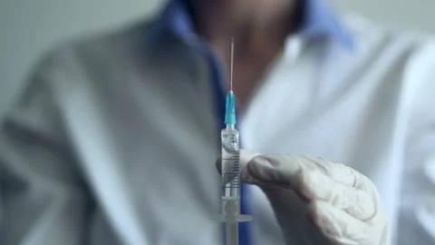 Doctor checking filled syringe with fluid Stock Footage 137122253