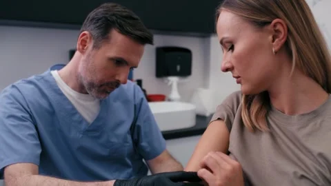 Doctor checking mark on woman's arm Stock Footage 274139988
