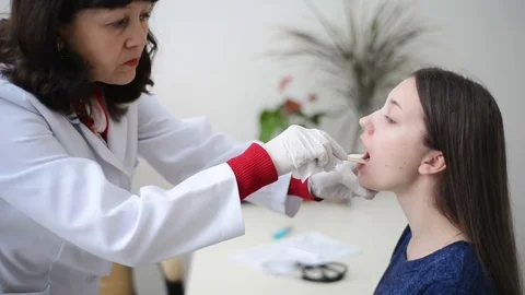 Doctor checking or examining throat swab test young female patient Stock Footage 77584133