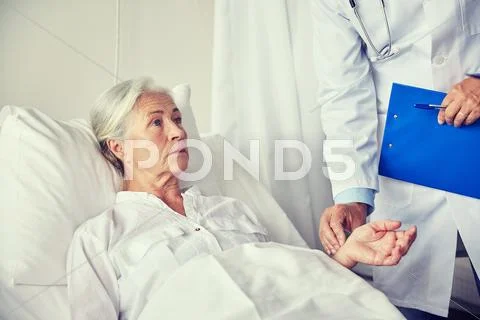 Doctor checking senior woman pulse at hospital Stock Photos