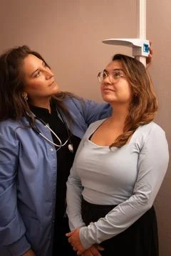 Doctor checking standing patient's height in clinic Foto stock
