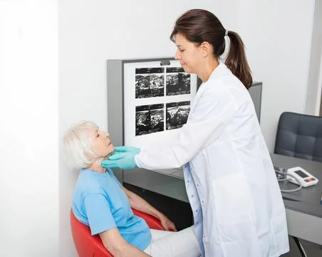 Doctor checking the thyroid gland of an elderly woman. Diagnosis of thyroid d Fotos Stock
