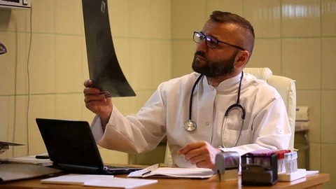 Doctor checking x-ray and telling bad news to the camera Stock Footage 77884917