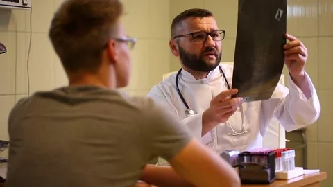 Doctor checking x-ray and telling bad news to the patient Stock Footage 77885035