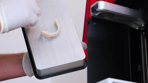 Doctor cleans teeth printed in a printer for work Stock Footage 277083858