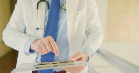 Doctor With Clipboard Using Digital Tablet In Corridor 4K Stock Footage 92435803