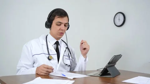 The doctor communicates via video communication while sitting in his office Stock Footage 144992476