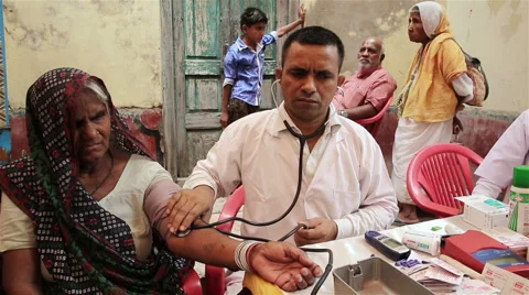 A doctor conducts a medical examination of older women outdoors in central India Stock Footage
