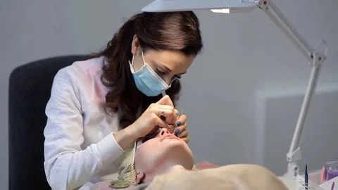 The doctor-cosmetologist performs the procedure of correction and escalating of Stock Footage 84588952