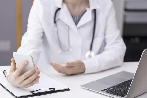 Doctor in a cubicle at a white table talking via video link Stock Photos