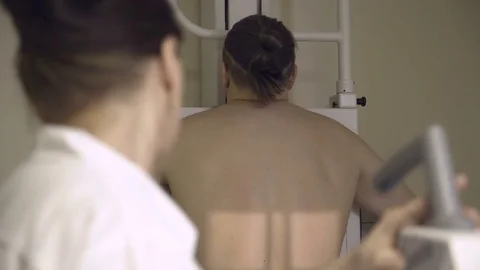 Doctor directs X-ray machine on a patient Stock Footage 72987643