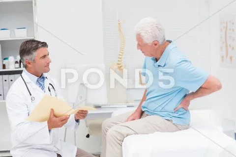 Doctor discussing reports with patient suffering from back pain Stock Photos