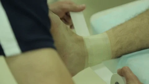 Doctor does a dressing, bandage on the ankle joint, close up Stock Footage 74388393