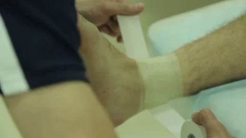 Doctor does a dressing, bandage on the ankle joint, close up Stock Footage 75987454