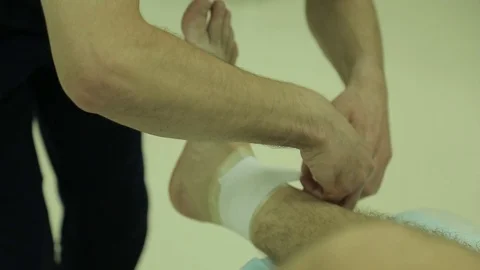 Doctor does a dressing, bandage on the ankle joint, m/s Stock Footage 75987468