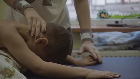 The doctor does neck exercises with the child in a rehabilitation center. Video stock 97299443