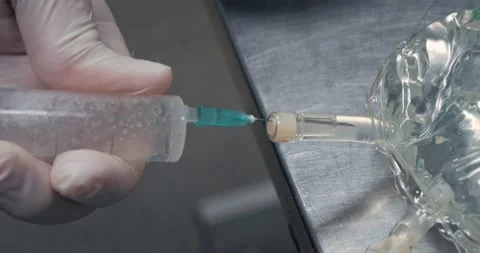 The doctor draws an injection solution into a syringe from a large bottle. Large Stock Footage 276096109