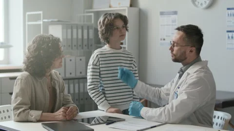 Doctor Examining Lymph Nodes of Kid and Talking to His Mother in Clinic Stock Footage 302019331