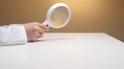 Doctor examining research data while holding a magnifying glass, focusing on Stock Footage 324762425