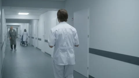 Doctor exiting the elevator and walking along the clinic corridor Stock Footage 249795536