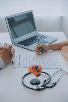 Doctor explaining brain functions to patient on model in office. 写真素材