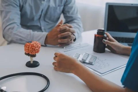 Doctor explaining brain functions to patient on model in office. 写真素材